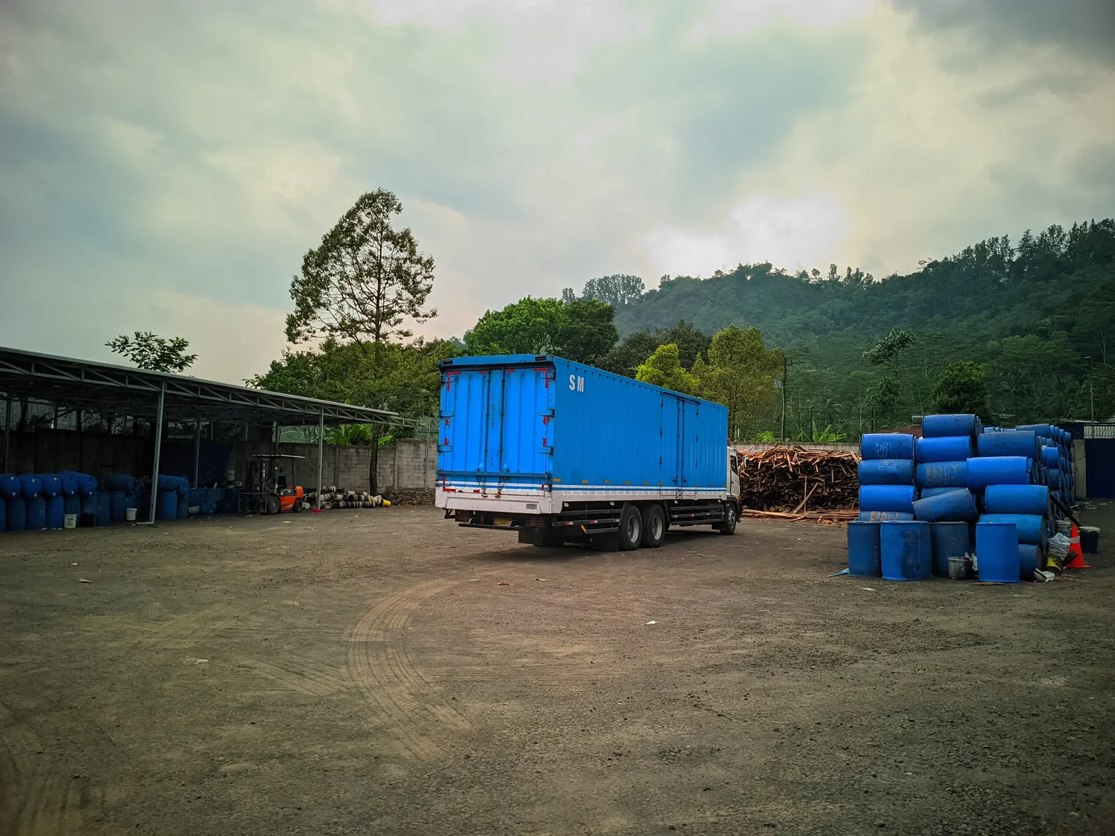 Halaman gudang: drum nira dan kayu bakar